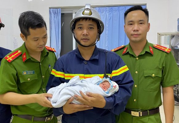 Thiếu tá Mạnh bế cháu bé khi bé được sơ cứu tại bệnh viện đa khoa huyện Gia Lâm tối 18/8. Ảnh: Công an cung cấp.